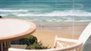 Vistes a la platja des d'un balcó amb taula i cadires, amb vista a l'oceà.