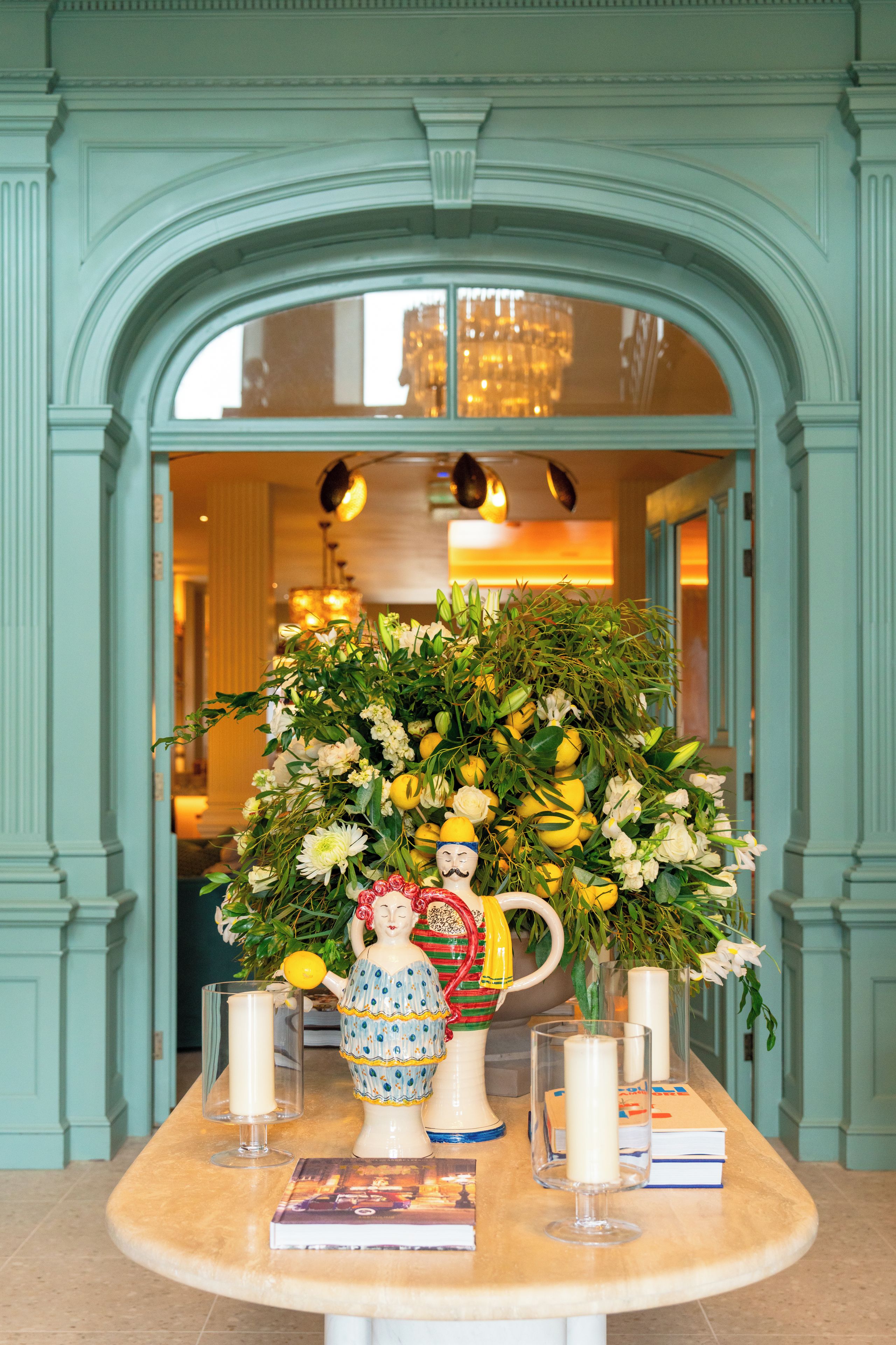 Une table ornée d’un vase de fleurs, de bougies et d’un pichet décoratif.