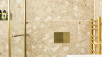 A bathroom with a shower, toilet, and sink, all with gold fixtures.