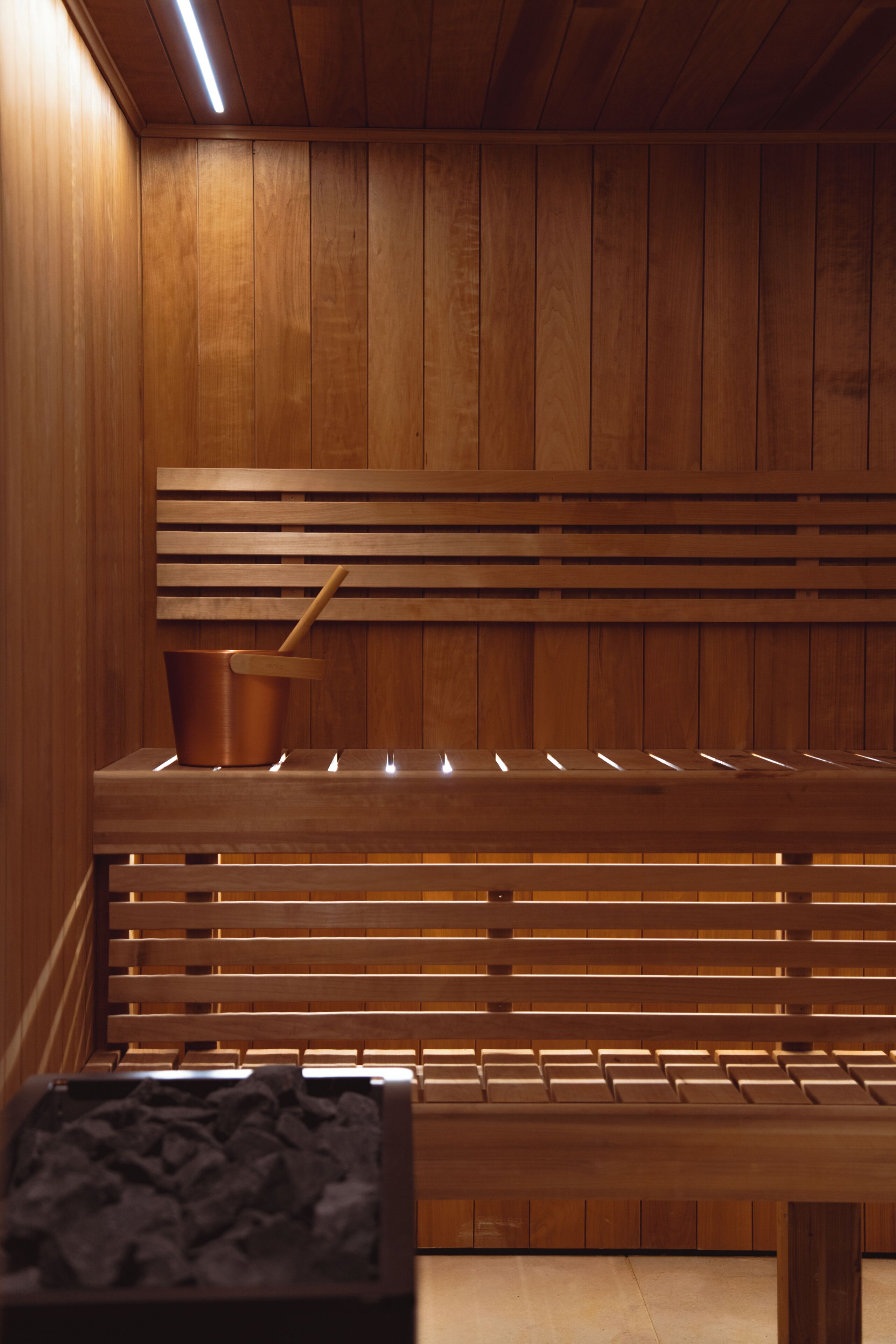 Uma sauna com bancos de madeira e design de parede em ripas.