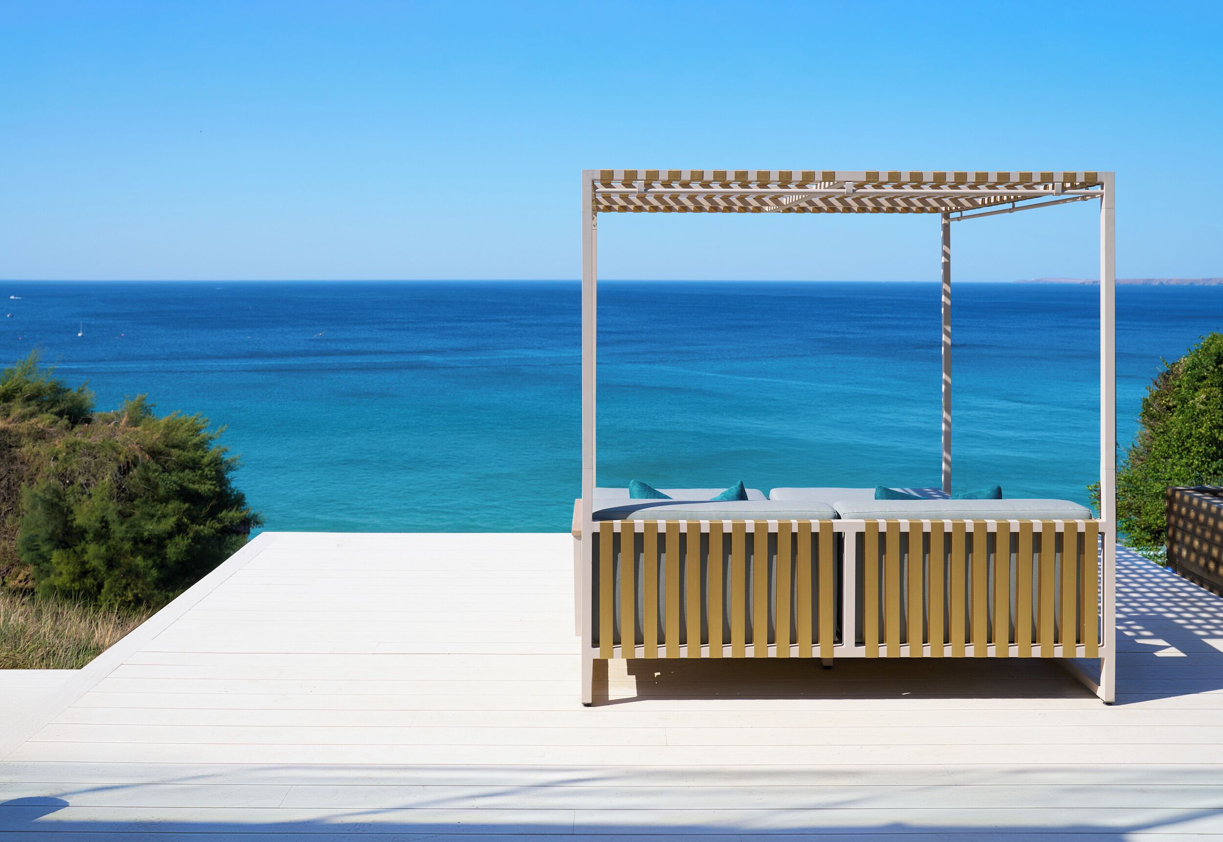 Un'area relax esterna in legno con vista sull'oceano.