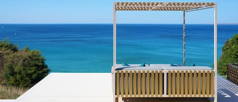 Un'area relax esterna in legno con vista sull'oceano.