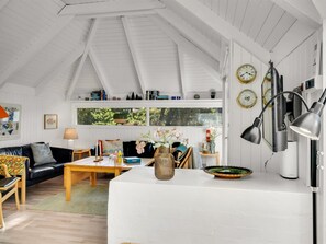 A cozy living room with a black leather sofa, a wooden coffee table, and a white table. There are books, a vase with flowers, and a clock on the wall. - "Udder" - 1.3km from the sea by Interhome (Fjerritslev)