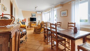 Un'area pranzo con tavolo e sedie in legno, televisione e divano.