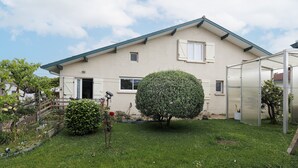 Una casa con un prato curato, un grande arbusto e un cielo sereno.