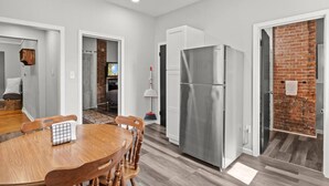 A modern kitchen with a stainless steel refrigerator, wooden dining table, and chairs.
