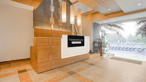Un comptoir d’accueil avec une enseigne indiquant « TOWNHOUSE, services aux entreprises », une entrée avec une porte vitrée et un guichet d’enregistrement.