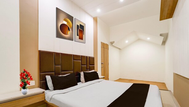 Une chambre d’hôtel moderne, dotée d’un grand lit, d’une table de chevet, d’une petite table, d’une lampe fixée au mur et d’un vase décoratif avec des fleurs.