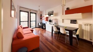 Ein zeitgemäßer Wohnbereich mit Sofa, Esstisch, Stühlen und Küchenzeile.