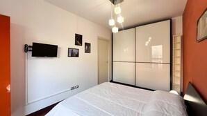 Ein Schlafzimmer mit einem Bett, einem Fernseher, einem Kleiderschrank und einer Tür.