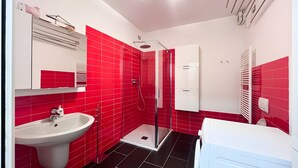 Ein Badezimmer mit Dusche, Waschbecken und weißen Schränken.