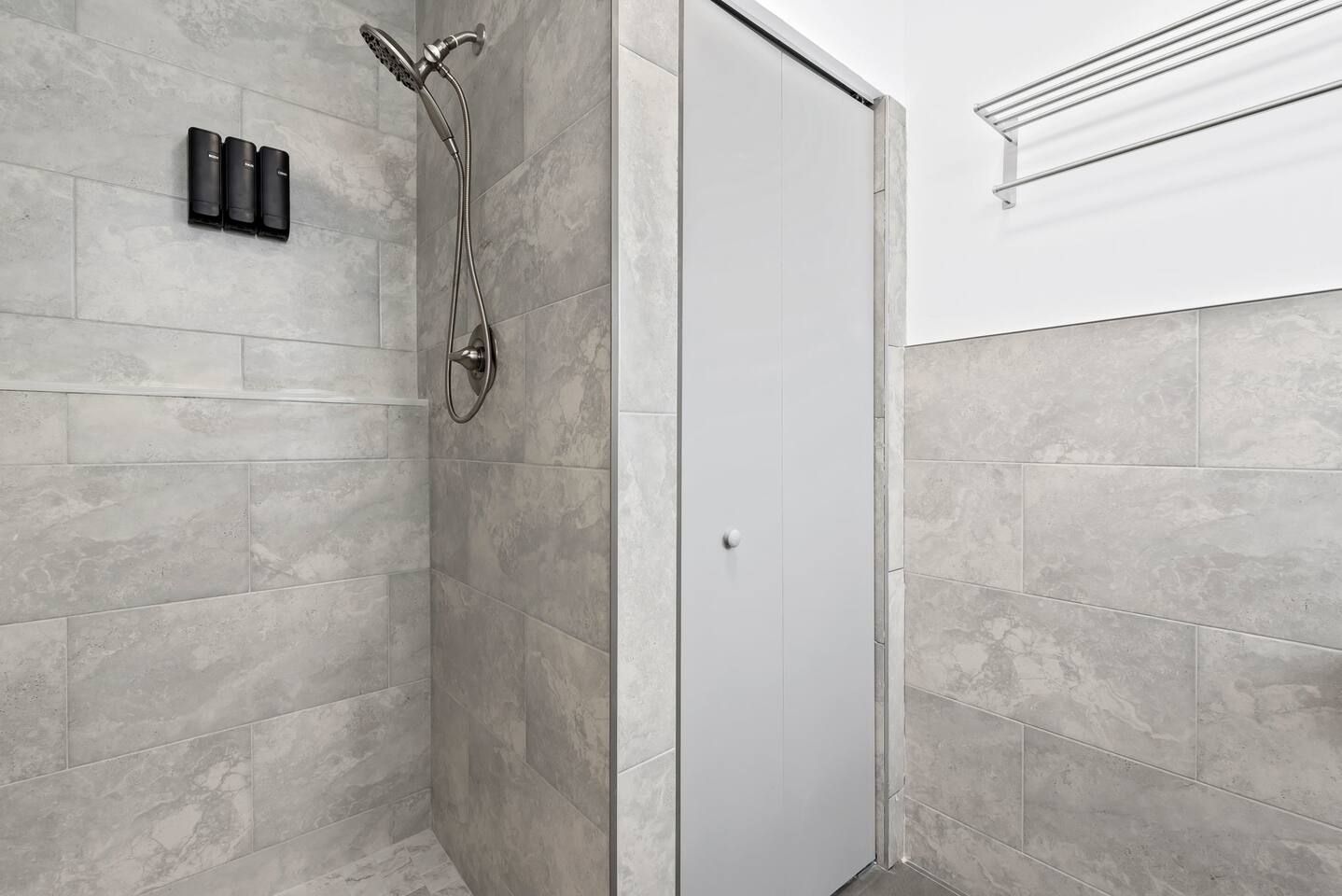 A shower area with a handheld showerhead and a wall-mounted faucet.