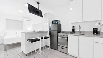 Eine kompakte Küche mit Kühlschrank, Herd, Backofen und einer kleinen Bar mit Hockern.