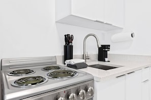 A modern kitchen with a stainless steel stove, a sink, and a coffee maker. - Private modern studio w/ pool - Steps to the beach (Deerfield Beach)
