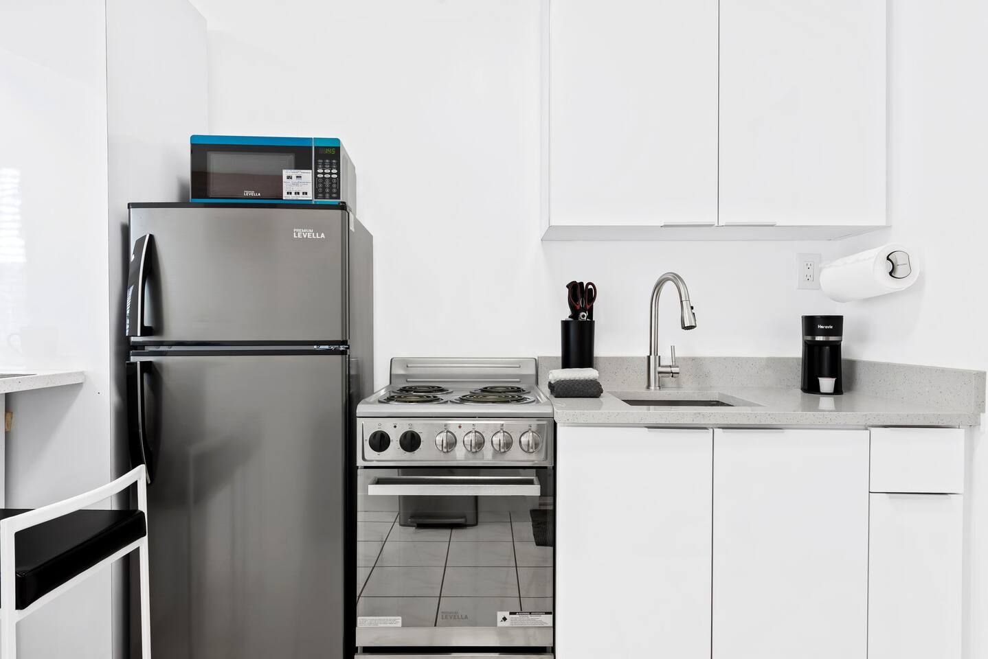 A modern kitchen with a stainless steel refrigerator, a stove, and a microwave.