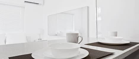 Un baño moderno con un espejo grande, una encimera con un lavabo y una taza, y un ventanal con persianas.