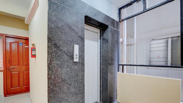 A hallway with a marble wall, a wooden door labeled '101', and a fire extinguisher. - Saver Singlehotel O Channasandra (Bengaluru)