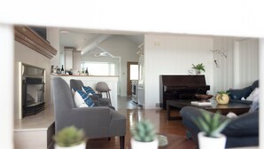 A modern living room with a fireplace, a piano, and a dining area. - On The Rocks • Waterfront Retreat Near Point Pelee (Leamington)