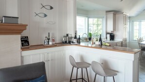 A kitchen with white cabinetry, a wooden countertop, two bar stools, and a sign indicating WiFi availability. - On The Rocks • Waterfront Retreat Near Point Pelee (Leamington)