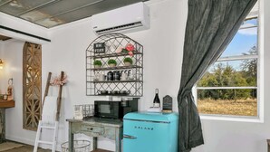Eine kleine Küche mit einem klassischen Galanz-Kühlschrank, einer Kaffeemaschine und einem Weinregal mit Blumentöpfen.