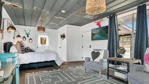 Ein Schlafzimmer mit einem Bett, einem Schreibtisch, einem Stuhl, einem Teppich und einem Fenster mit Vorhängen.
