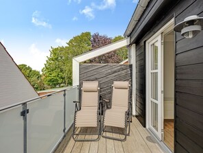 A balcony with two beige lounge chairs, a wooden deck, and a dark wooden building with a white window. - "Alwina" - 900m from the sea by Interhome (Bindslev)