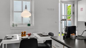 Ett modernt kök med en matplats, en hängande taklampa och utsikt genom fönstret.