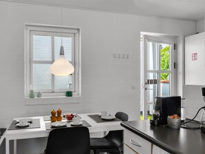 A modern kitchen with a dining area, a hanging pendant light, and a view through the window. - "Alwina" - 900m from the sea by Interhome (Bindslev)