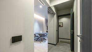 En moderne gang med spiseplads, en dør med greb og en lampe i loftet.