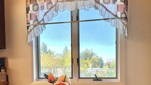 A dining area with a table, chairs, a window with a view, and a vase with flowers.