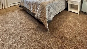 A bedroom with a bed, a nightstand, a lamp, and a window with curtains.