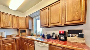 A kitchen with wooden cabinets, a dishwasher, a coffee maker, and a toaster.