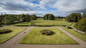 Un jardín bien cuidado con un parterre circular en el centro, rodeado de césped impecable y senderos.