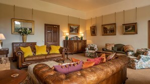 Una sala de estar con sofás de cuero, un aparador de madera y obras de arte enmarcadas en las paredes.