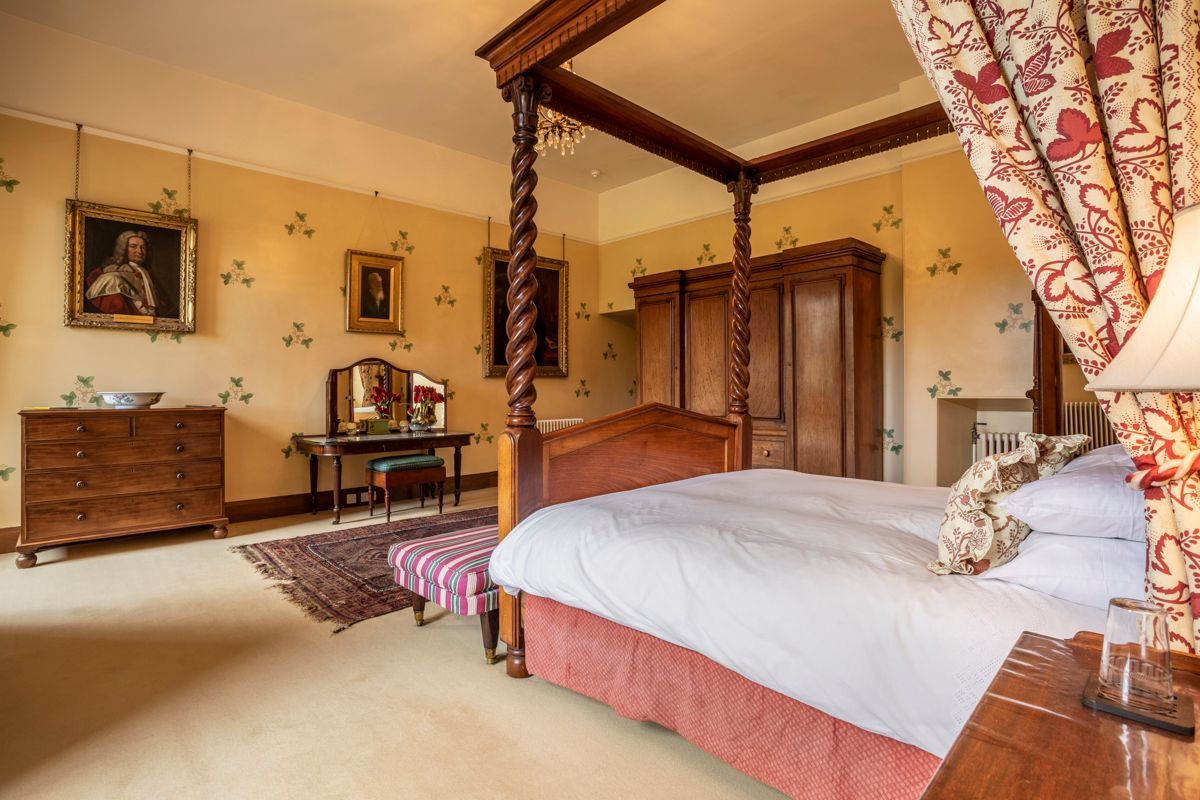 A bedroom with a four-poster bed, a dresser, a desk, and a chair.