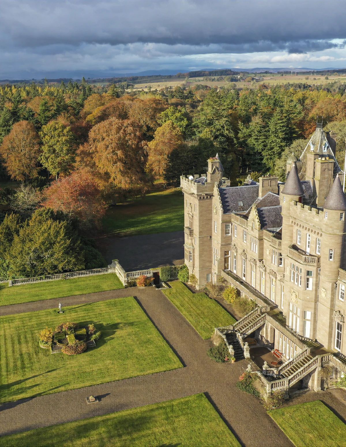 Un grand château doté de nombreuses tours, d’une pelouse bien entretenue et d’un fossé.
