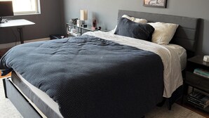 Une chambre à coucher avec un lit, des tables de chevet, un bureau et une fenêtre.