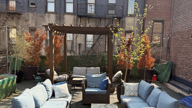 Un espace extérieur aménagé avec des meubles en osier, une pergola et des plantes en pot.