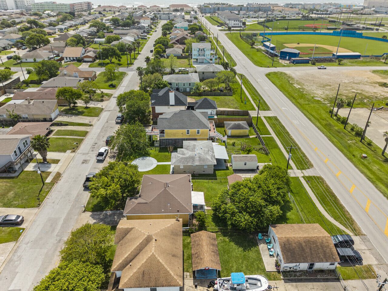 An aerial view of a residential neighborhood with houses, streets, and a baseball field.