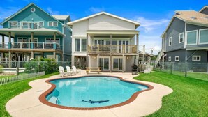 Un barrio residencial con piscina, una casa de dos pisos y un patio cercado.