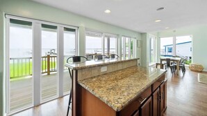 Una cocina amplia con encimera de granito, ventanas grandes y vistas al exterior.