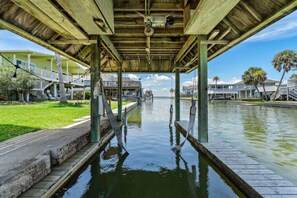A waterfront property with a covered dock, a grassy area, and a view of the water.