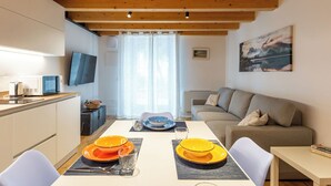 Een moderne keuken met een flatscreen televisie, een eettafel gedekt met oranje borden en een bank in de woonkamer.