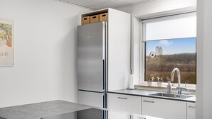 Una cucina moderna con frigorifero in acciaio inox, forno a incasso, una finestra vista campagna e un lavello con rubinetto.
