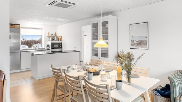Una cucina moderna con zona pranzo, mobili bianchi e vista sull'esterno.