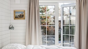 Una camera da letto con un letto, un quadro appeso al muro e vista attraverso una porta in vetro.