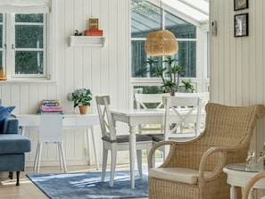 A bright room with white walls, a dining table, chairs, a wicker chair, a small white table, and a hanging light fixture. - "Sighvat" - 225m from the sea by Interhome (Gilleleje)