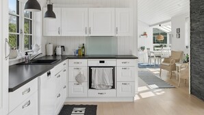 Una cucina moderna con mobili bianchi, piani di lavoro neri e illuminazione a sospensione.