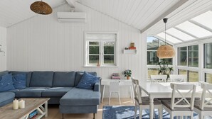 Un soggiorno moderno con un divano componibile, un tavolo da pranzo con sedie, una grande finestra e una ventola a soffitto.
