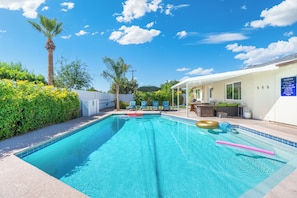 A swimming pool with clear blue water, surrounded by greenery and a white building with a blue roof. - Desert Diamond - Scottsdale 4 BR, Pool, Fire Pit, Ping Pong and games (Scottsdale)